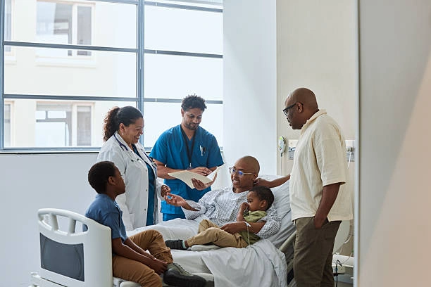 A patient in a hospital bed surrounded by family and medical staff, reflecting compassionate care at a cancer center in Jamaica.